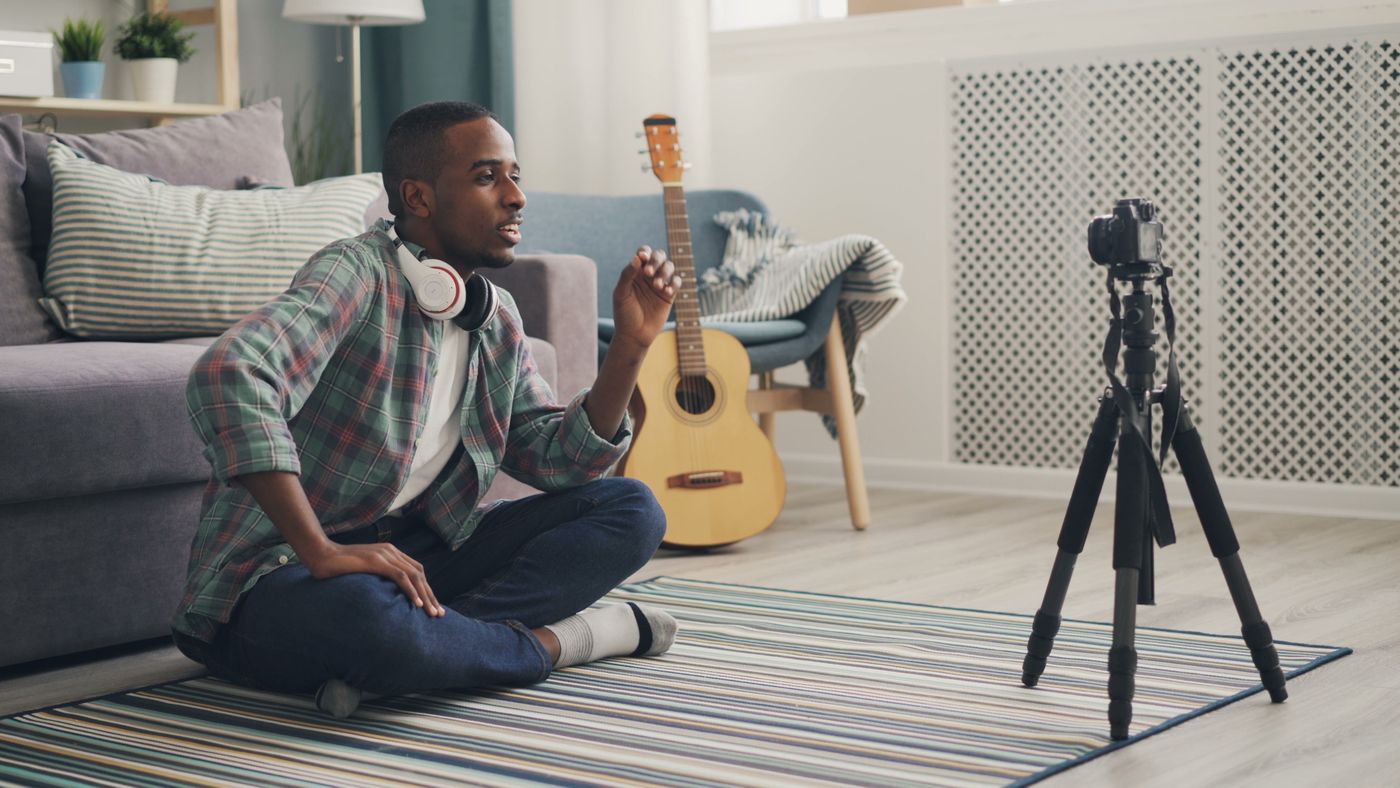 A content creator filming a promo video at home with a camera on a tripod